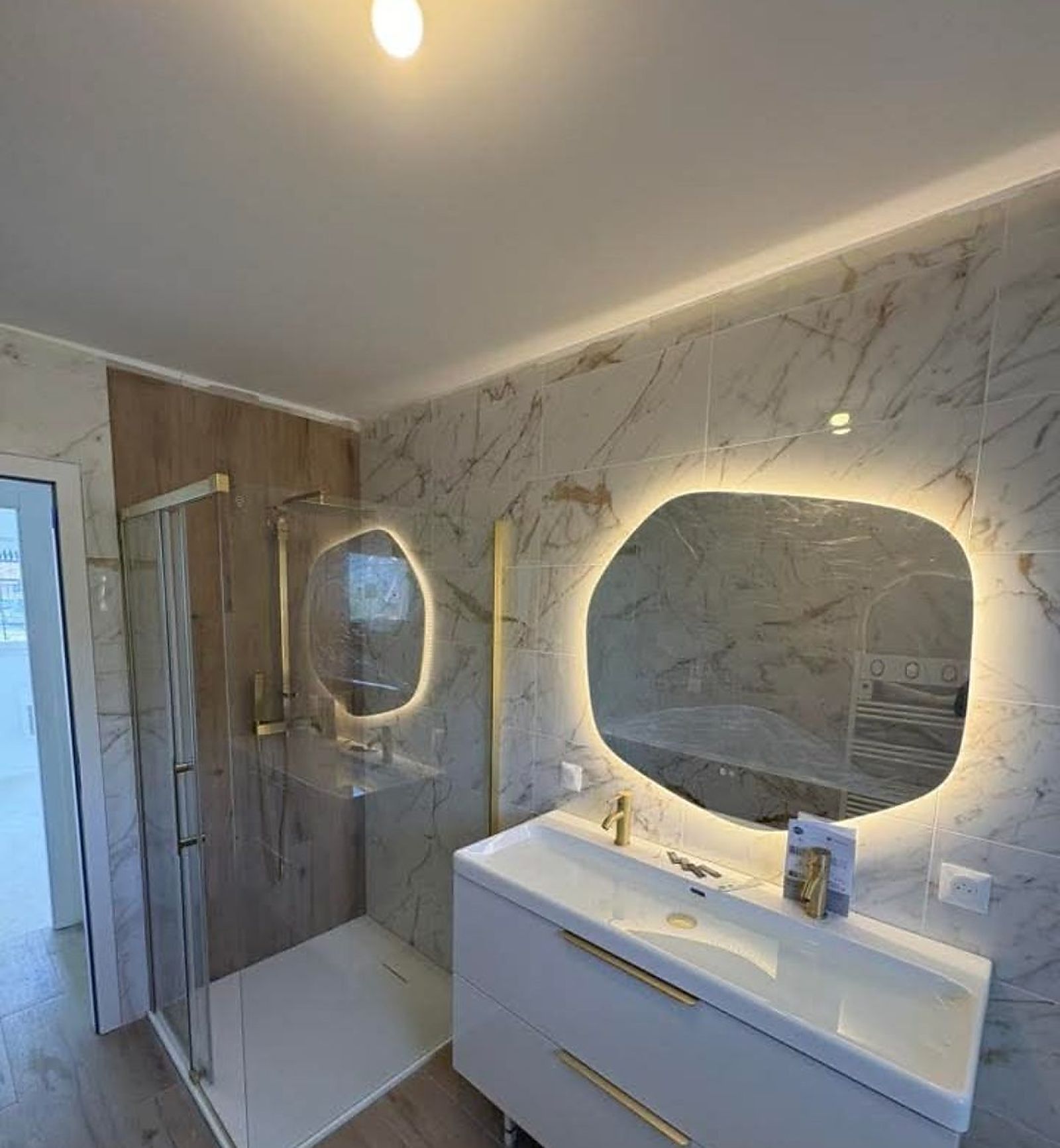 Salle de bain rénovée avec miroir rétroéclairé et robinetterie dorée, réalisée par DS Sanitaire & Chauffage
